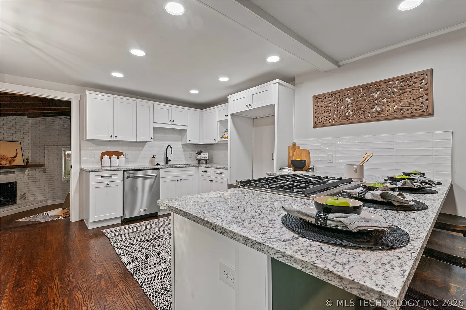 White kitchen remodel with granite island and gas cooktop